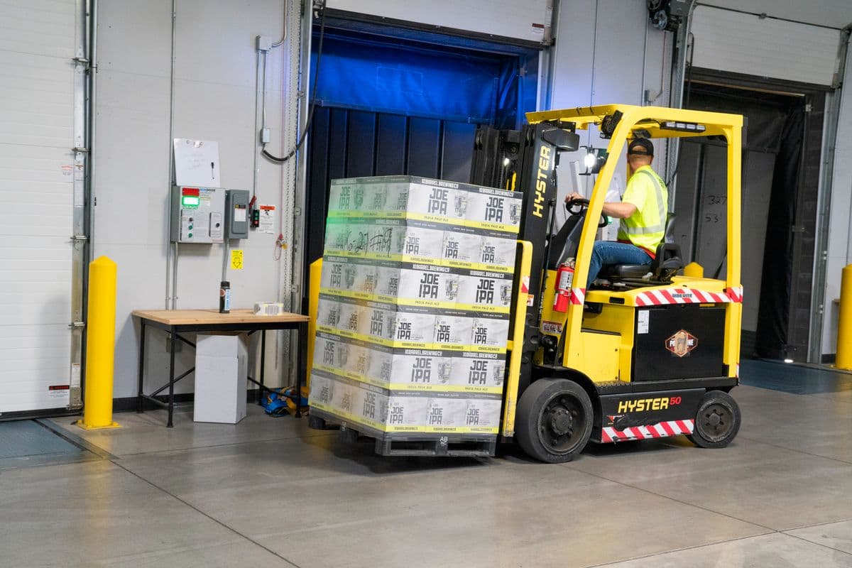 Forklift operator moving palletised goods in a warehouse