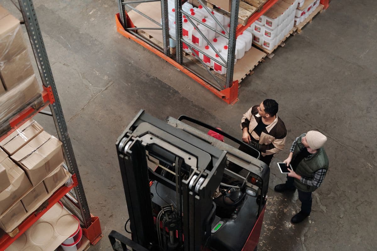 Trainer and operative reviewing forklift operations in warehouse